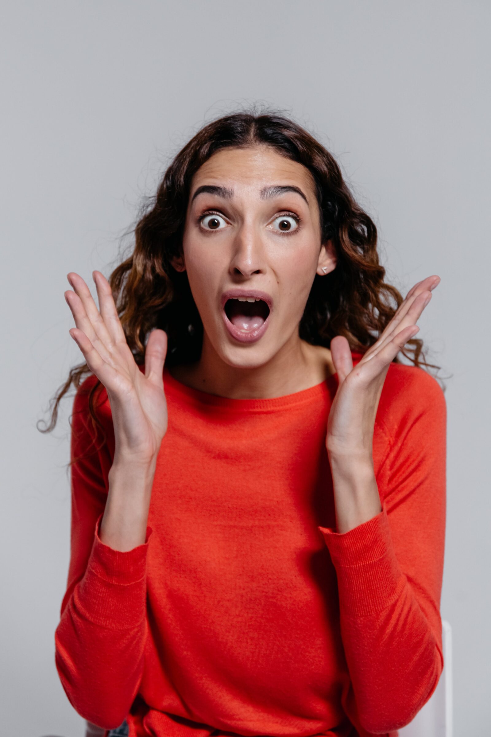 Woman in Orange Crew Neck Long Sleeve Shirt Feeling Surprised