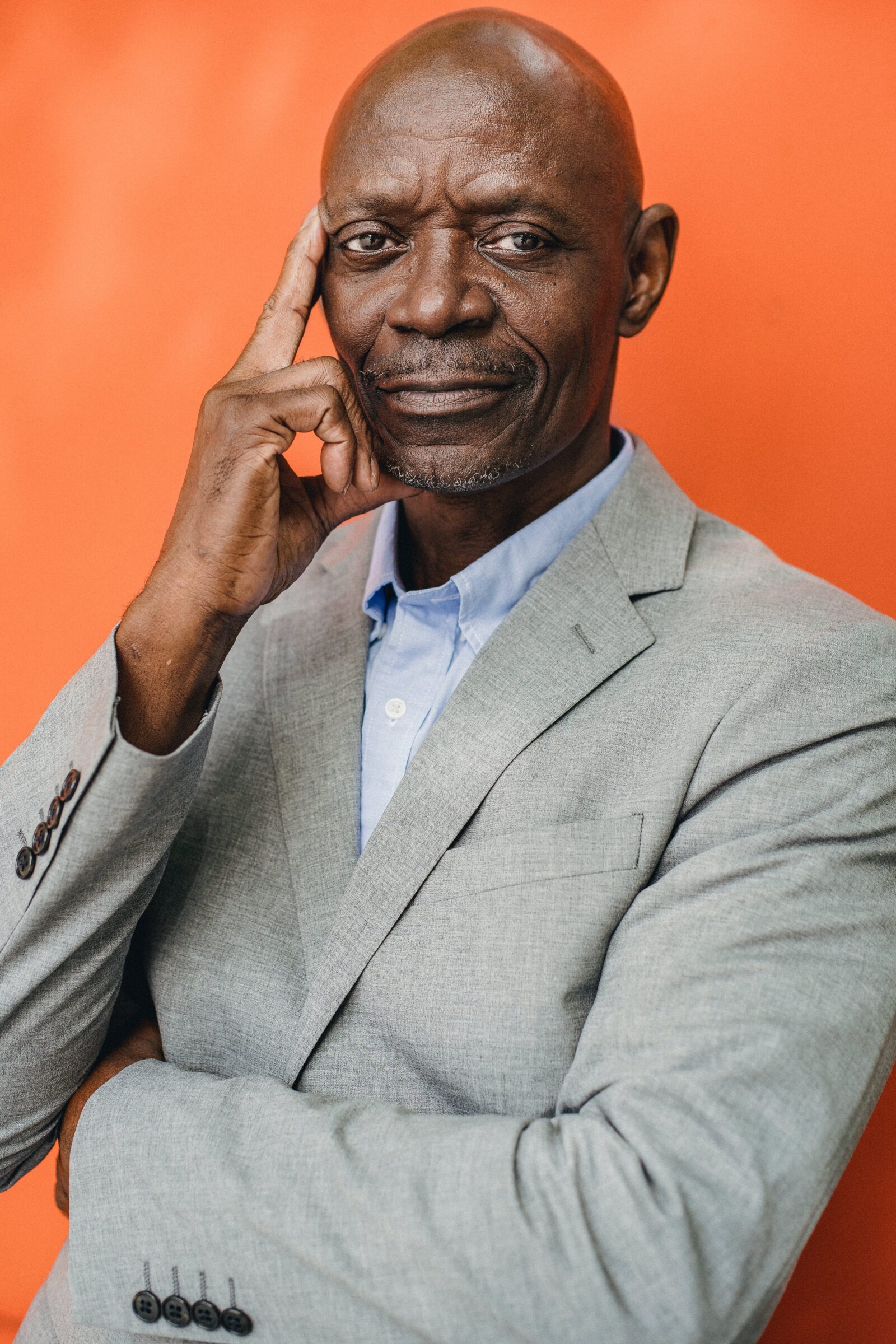 Intelligent black businessman in suit on orange background